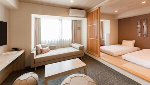 Een moderne hotelkamer met een bank, een bed, een bureau en een televisie.