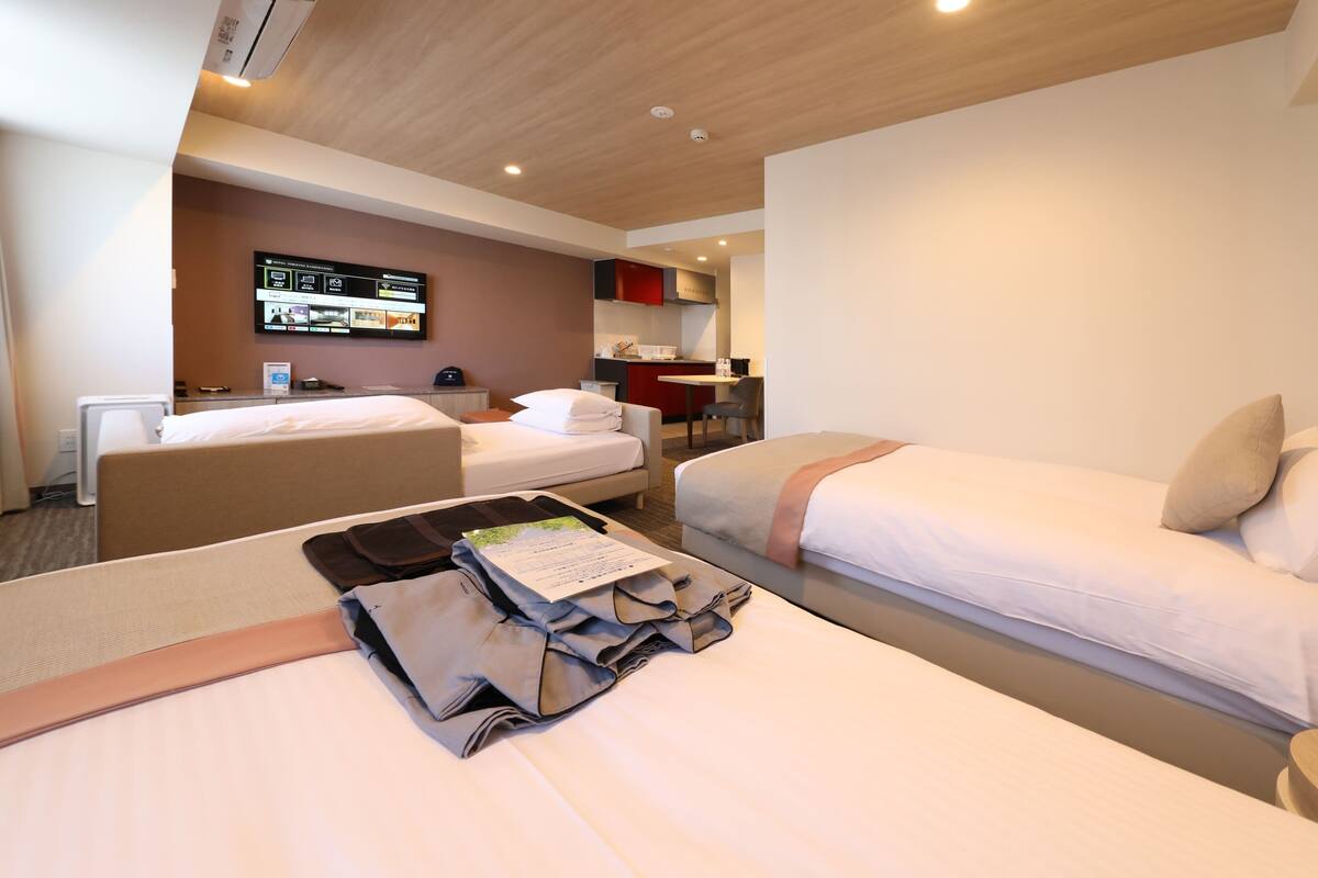 Une chambre d’hôtel avec deux lits, un bureau, une télévision et une kitchenette.