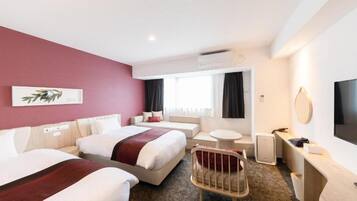 A hotel room with two beds, a small round table, a chair, a desk with a flat-screen TV, and a wall-mounted air conditioner.