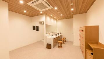 A modern bathroom with a wooden ceiling, a vanity with a mirror, and a wooden cabinet with drawers.
