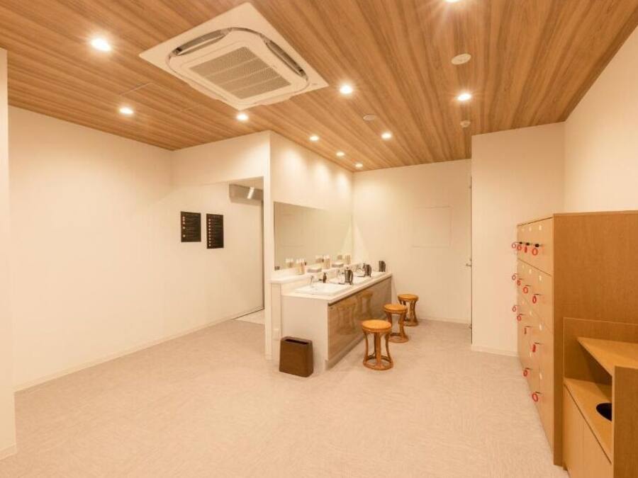 A modern bathroom with a wooden ceiling, a vanity with a mirror, and a wooden cabinet with drawers.