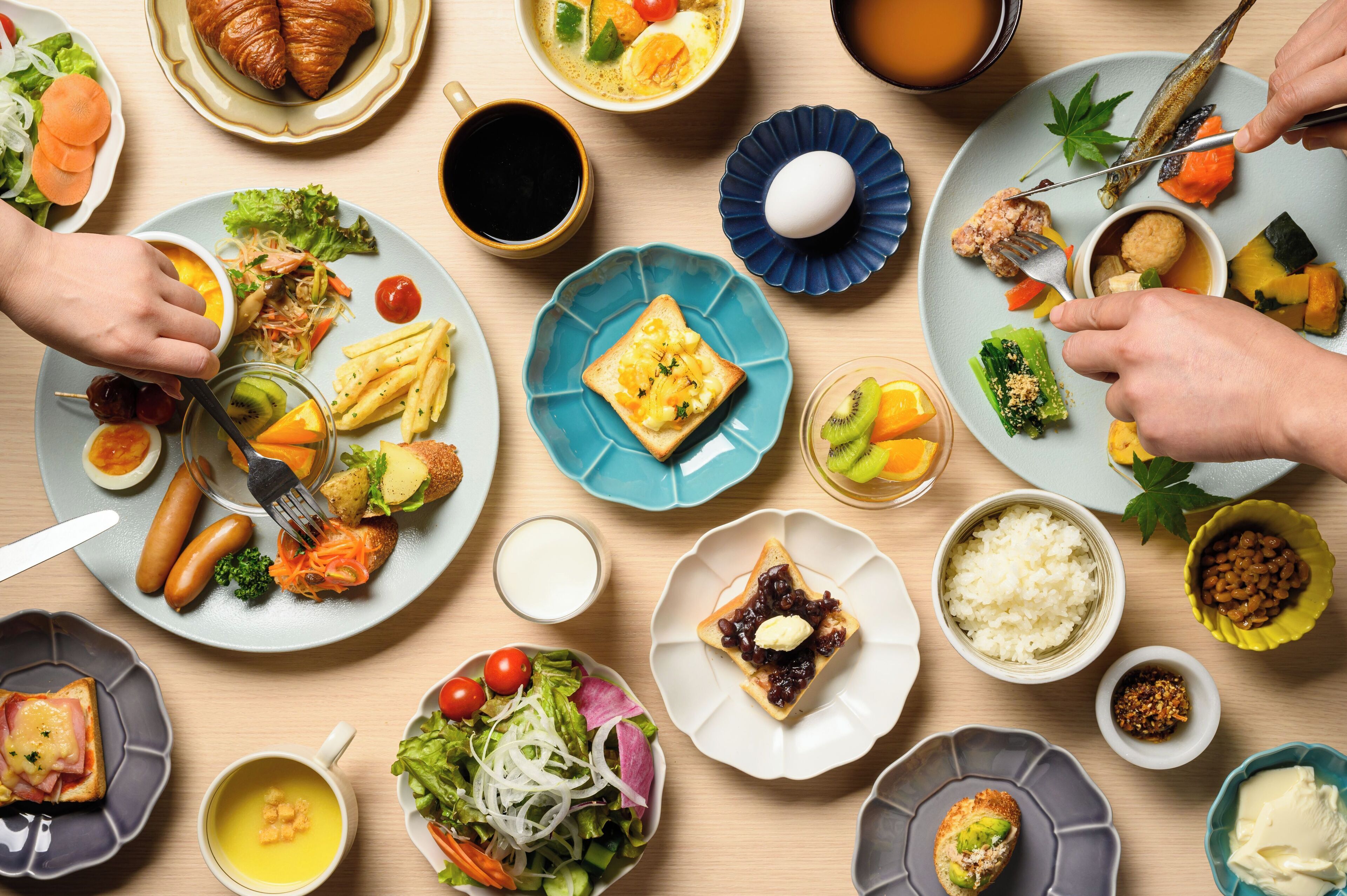 Ein Tisch mit verschiedenen Speisen, darunter Croissants, Salate und eine Auswahl an Obst und Gemüse.