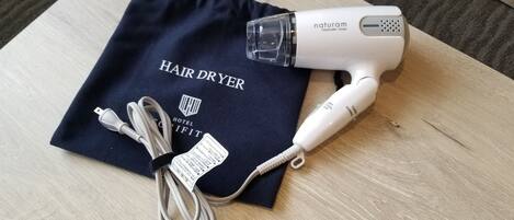 Un secador de pelo y sus accesorios sobre una superficie de madera.