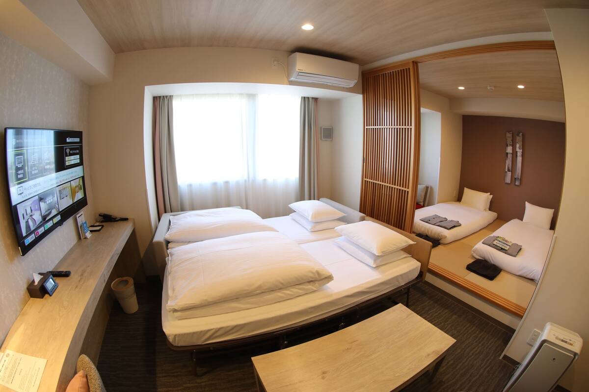 Une chambre d’hôtel avec deux lits, un bureau, une télévision et un appareil de climatisation.
