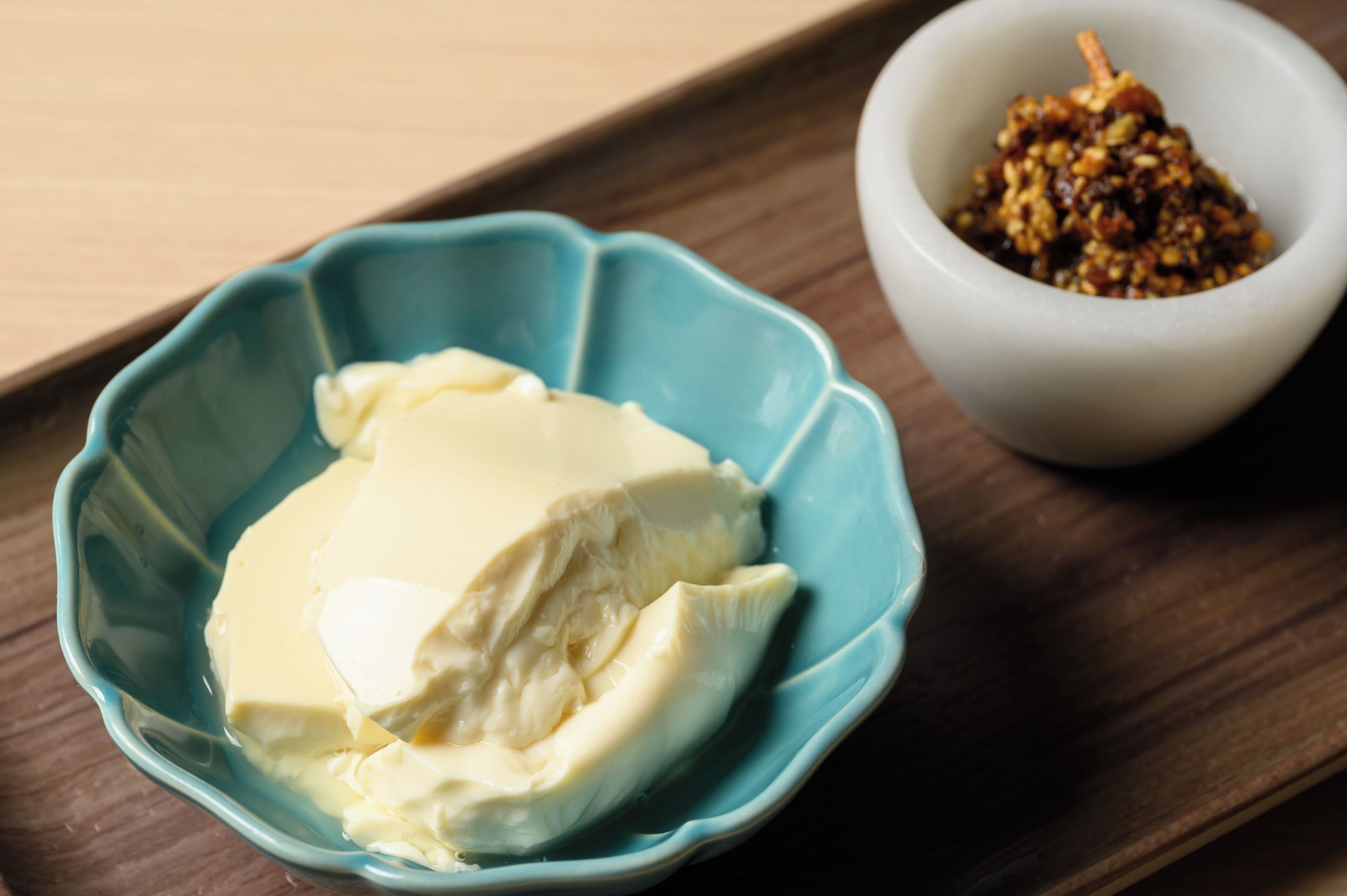 A blue bowl with a white substance, possibly butter, and a white bowl with a brown mixture.