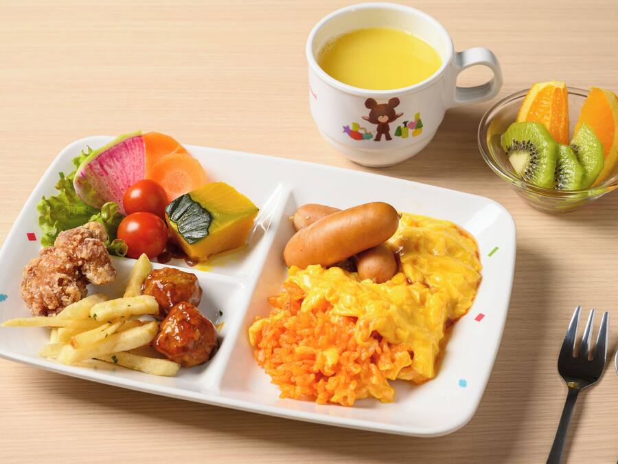 Uma refeição com diversos pratos, incluindo ovos, salsichas e vegetais, servida em um prato branco.