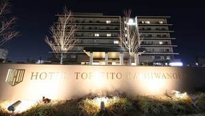 Een hotelbord met de naam 'HOTEL TOP FITO KASHIWANOHA' verlicht in de nacht.