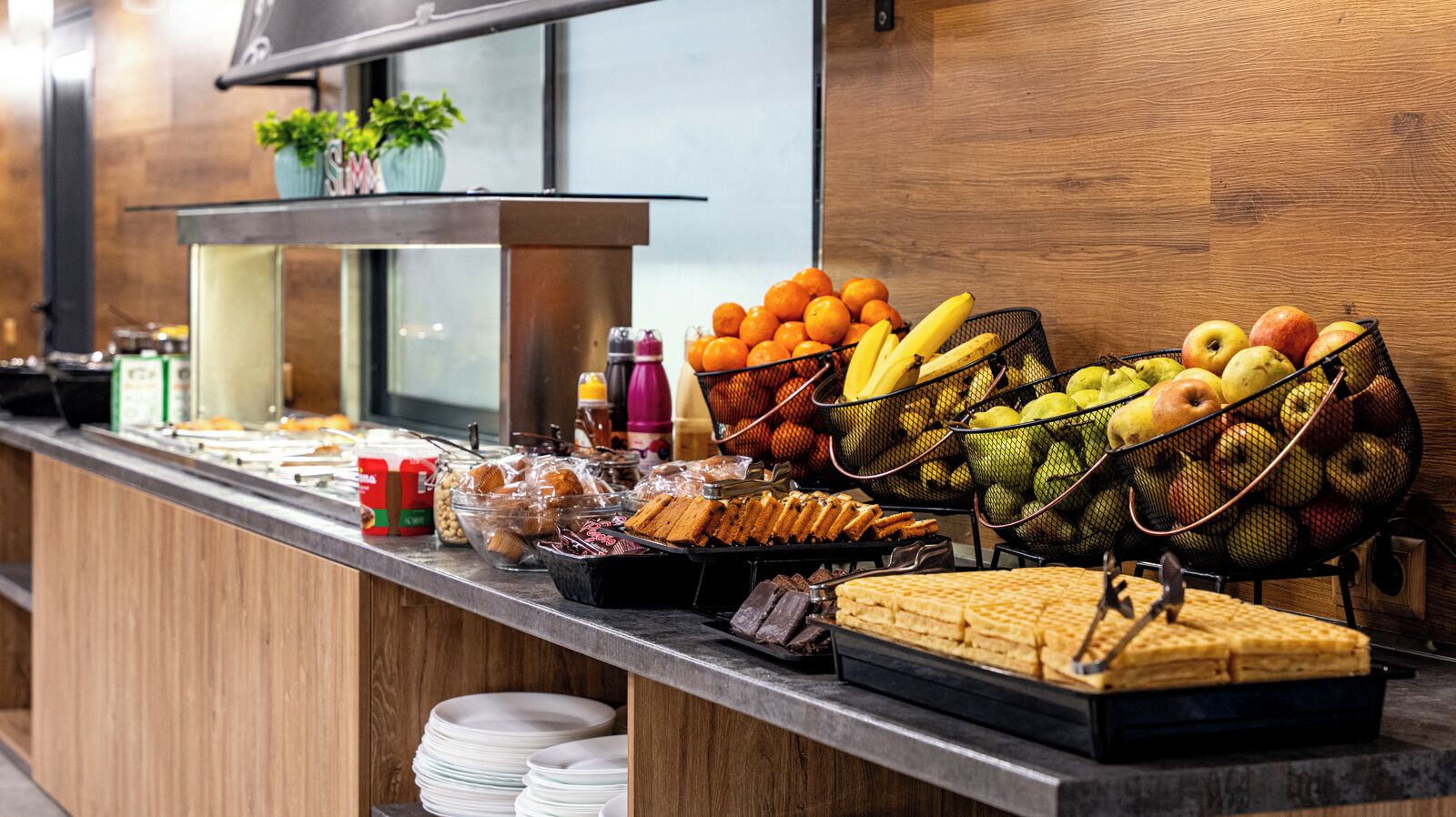 Un buffet proposant une variété de plats, notamment des fruits, des pâtisseries et des boissons.