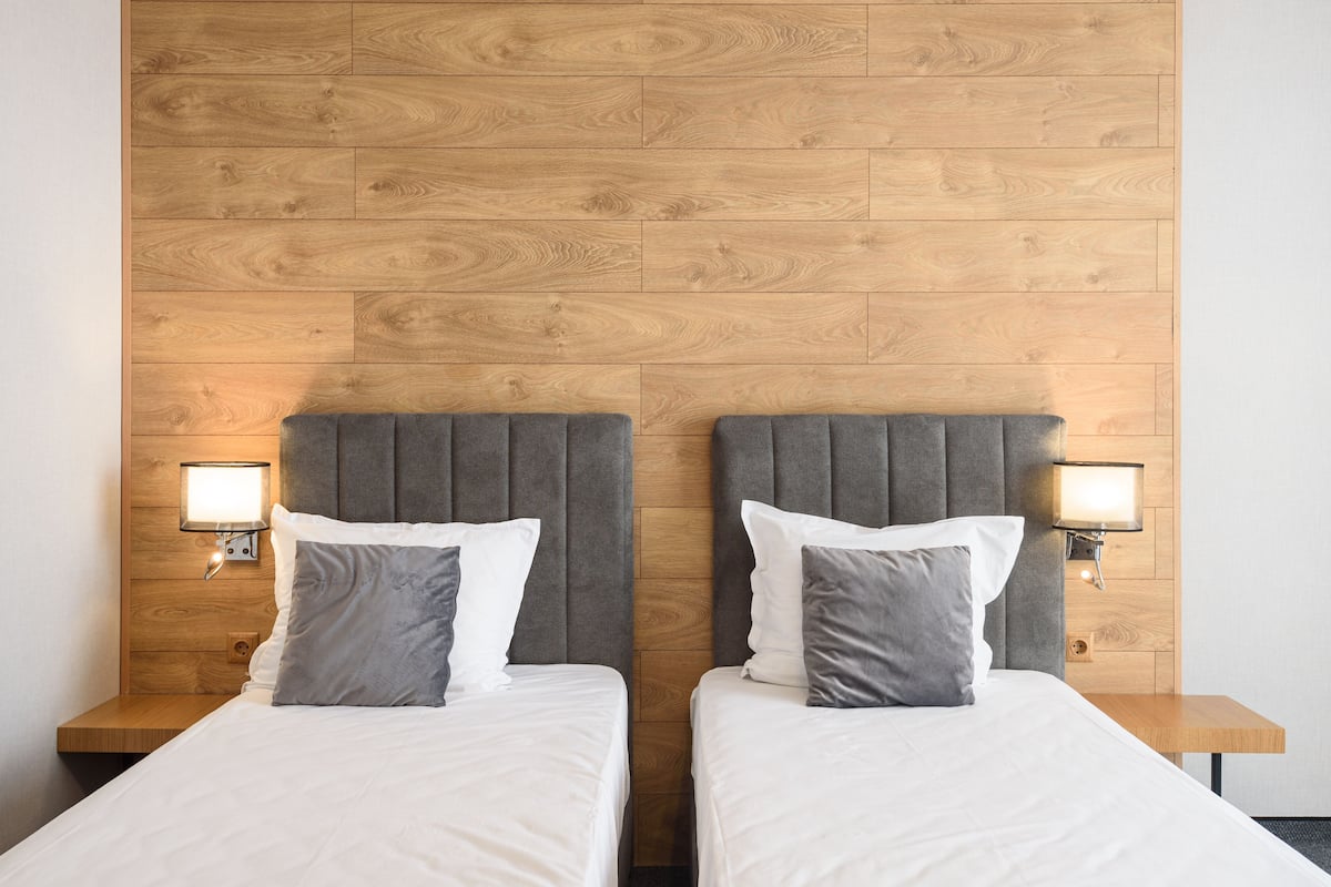 A hotel room with two beds, wooden headboards, and bedside lamps.