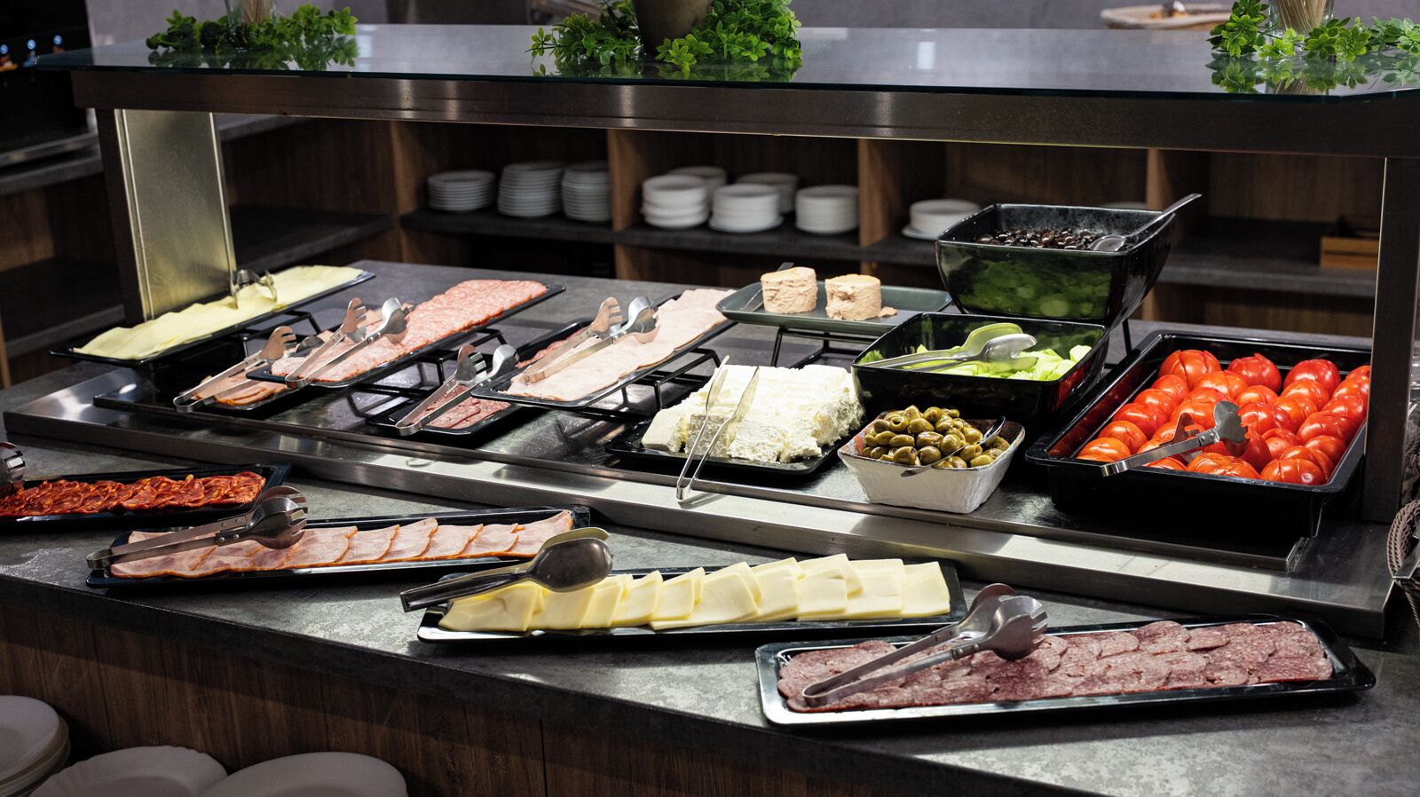 Buffet amb diversos aliments, com ara carns, formatges, olives i tomàquets.