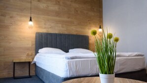 Un dormitorio con cama, mesitas de noche, una planta en maceta e iluminación colgante.
