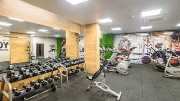 A gym with various exercise equipment, including dumbbells, treadmills, and stationary bikes.