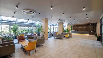A spacious lobby with modern furniture, a reception desk, and large windows allowing natural light.