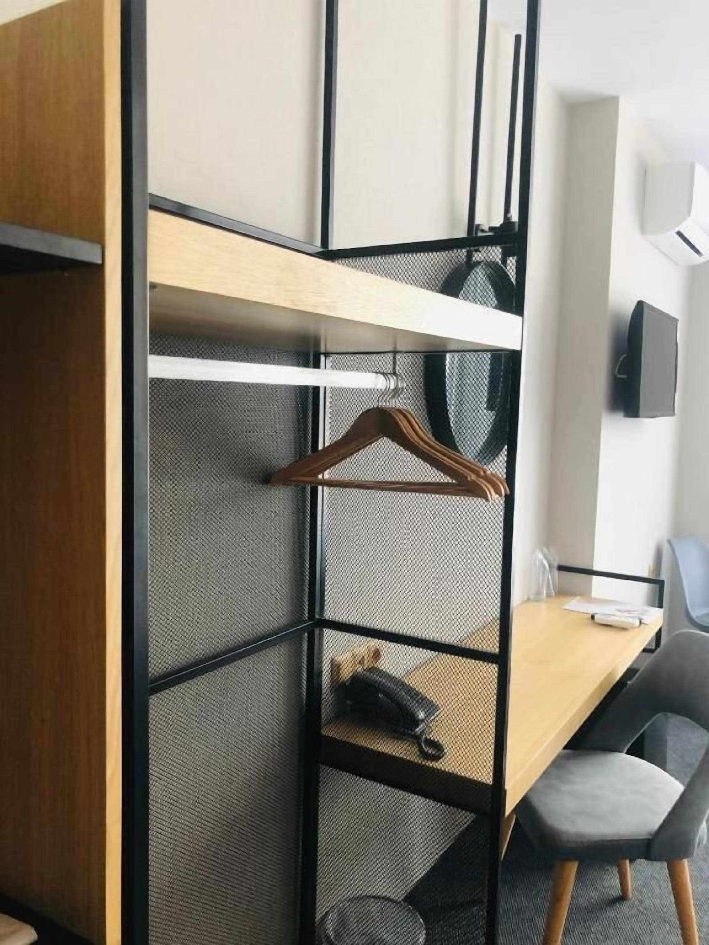 Ein Zimmer mit einer abgegrenzten Schreibtischzeile, einem an der Wand montierten Fernseher und einem Kleiderhaken.