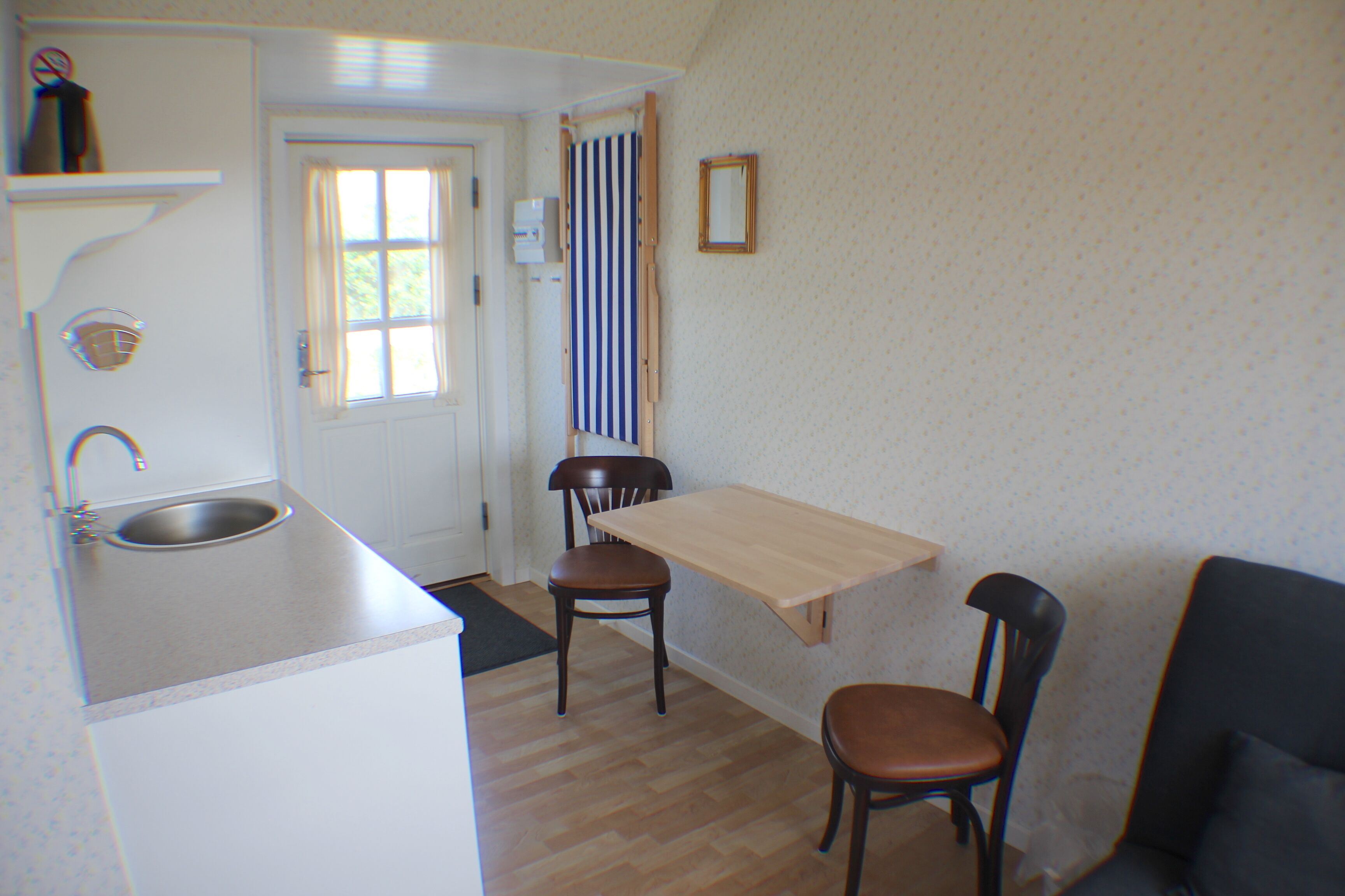 A small kitchen with a sink, a wooden table, and two chairs.