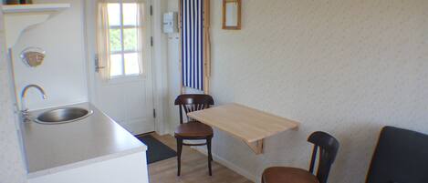 A small kitchen with a sink, a wooden table, and two chairs.