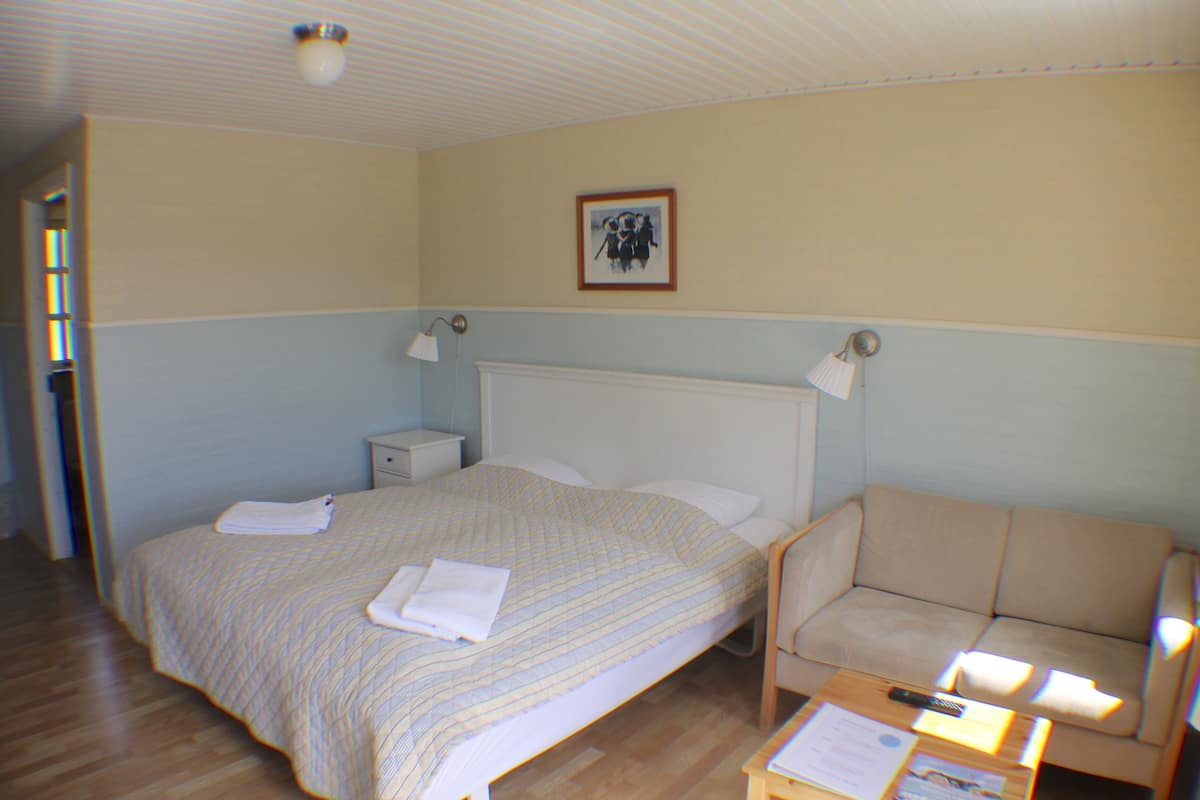 Ein Hotelzimmer mit Bett, Stuhl, Nachttisch und einer Wandlampe.
