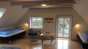 Un dormitorio abrigado y luminoso en el ático, con dos camas, una mesa de comedor y una silla.