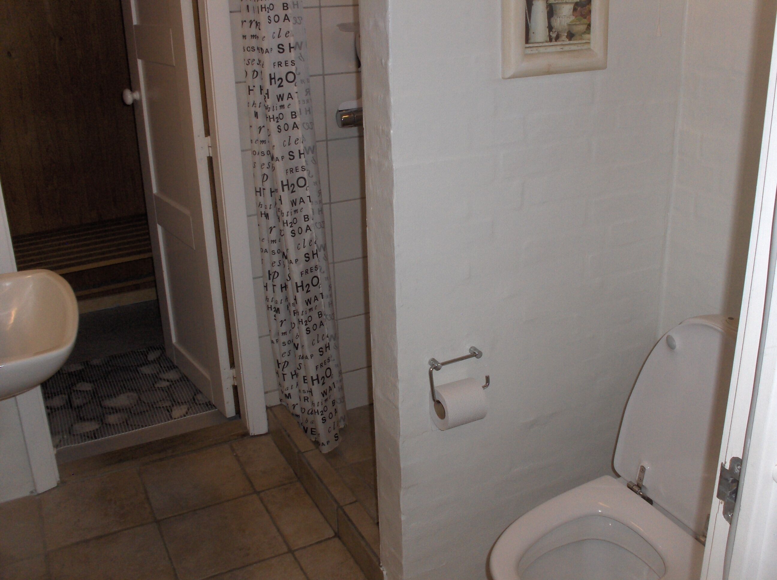 Une salle de bain comprenant des toilettes, un lavabo et un espace douche.