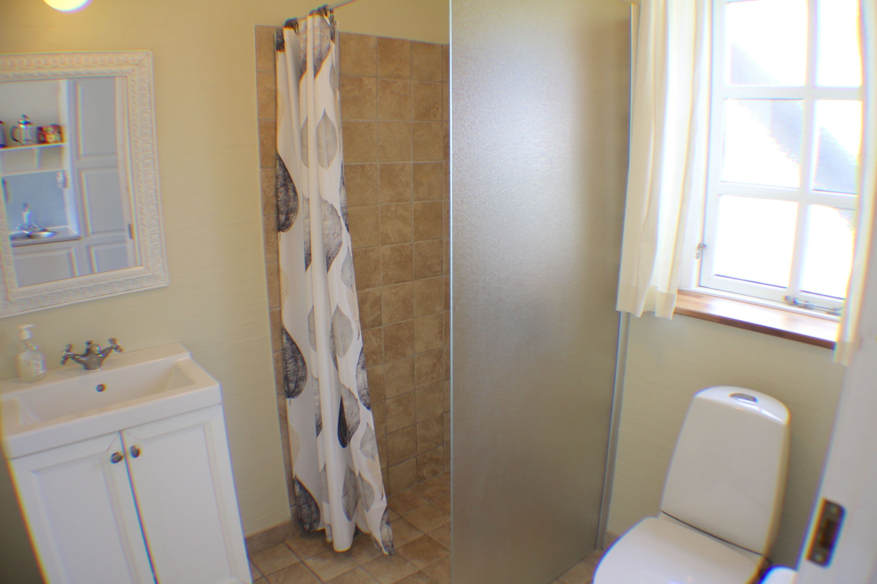 A bathroom with a shower curtain, a sink, and a toilet.