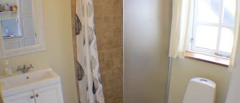 Un baño con cortina de ducha, lavamanos e inodoro.
