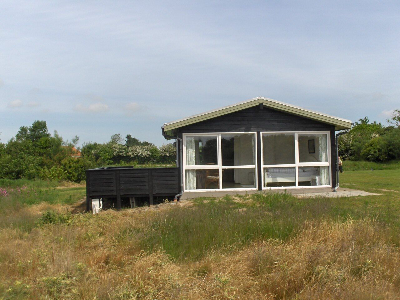 A modern house with a large glass window and a wooden deck.