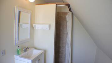 A bathroom with a sink, mirror, and shower curtain.