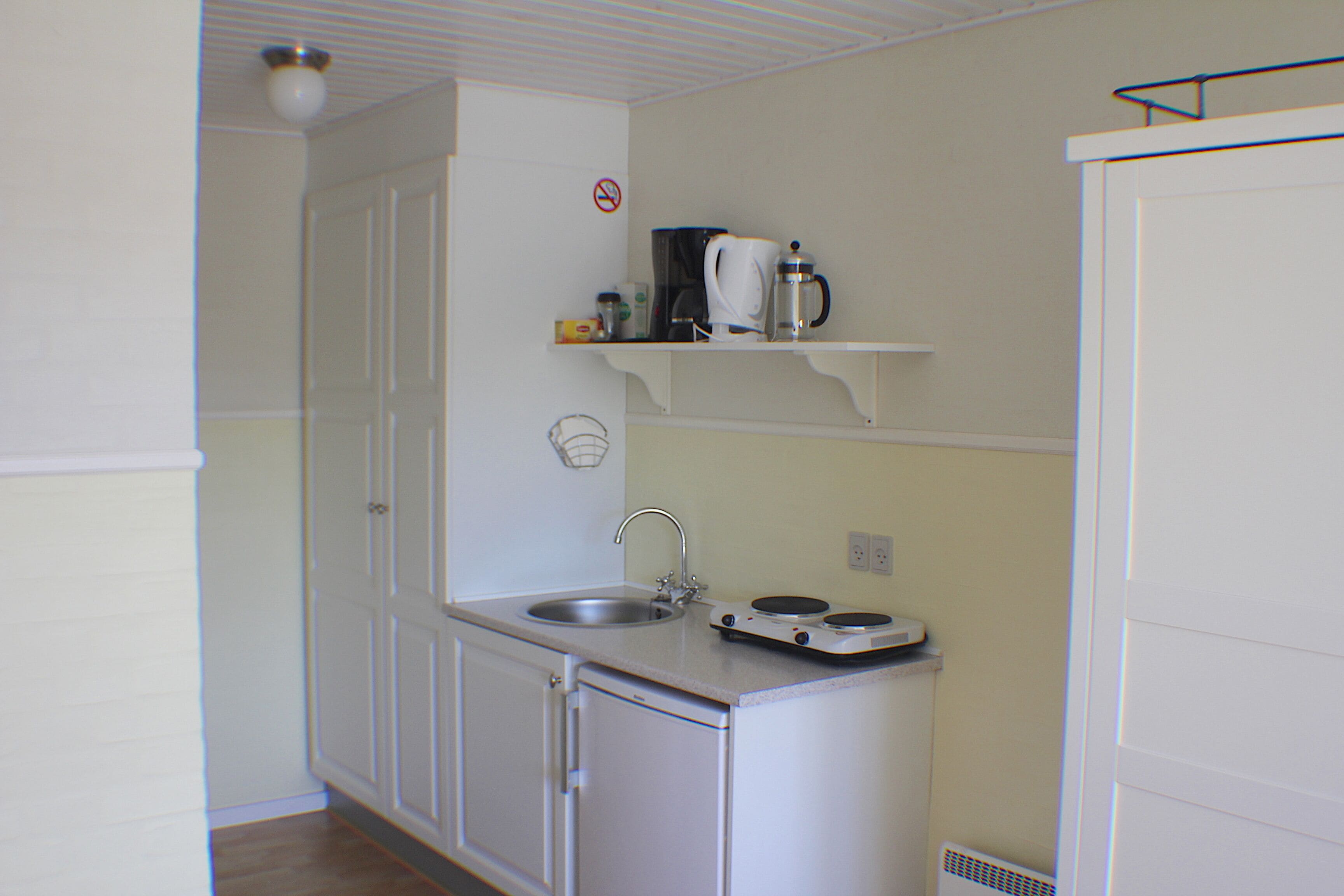 A small kitchenette with a sink, a coffee maker, and a stove.