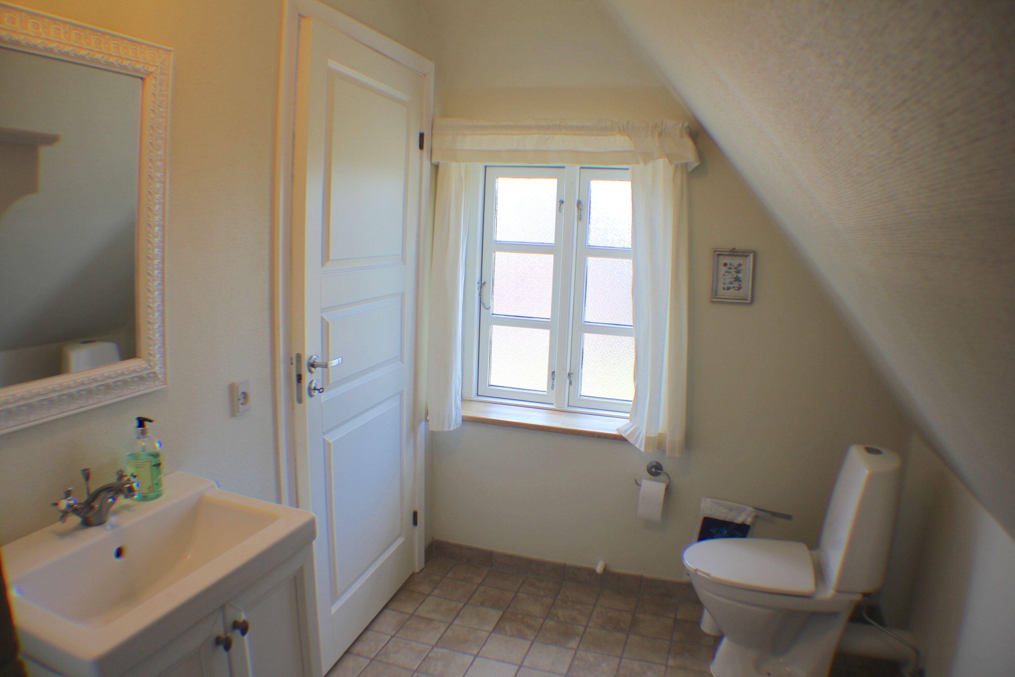 A bathroom with a sink, toilet, and window.