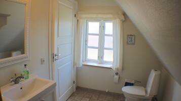 A bathroom with a sink, toilet, and window.