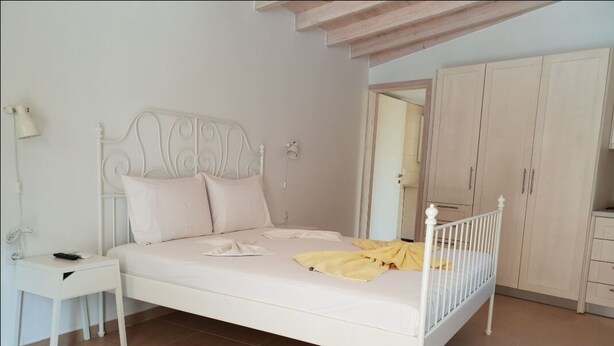 Une chambre à coucher avec un lit en métal blanc, une table de chevet, une lampe et une armoire.