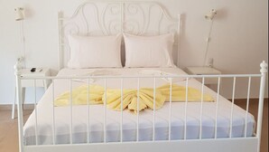 Un lit en métal blanc avec deux oreillers blancs et une serviette jaune.