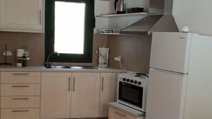 Une cuisine compacte avec des meubles de couleur claire, un four encastré, un réfrigérateur et une fenêtre donnant sur un beau paysage.