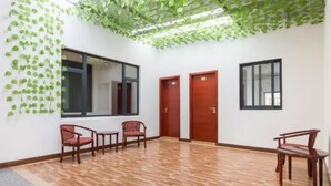 A room with a wooden floor, two wooden doors, and three wooden chairs. - Floral Hotel Dianhu Holiday Shanghai (Shanghai)
