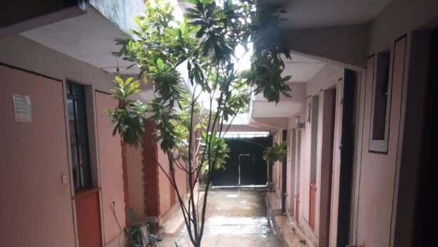 A corridor with a potted plant, tiled floor, and doors on both sides. - Club Woodland (Matuu)