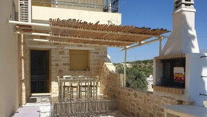 A stone patio with a pergola, outdoor seating, and a wood-fired oven. - Villa Sofia (Faistos)