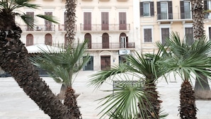 A courtyard with palm trees and a building with multiple balconies and windows. - "LULLABY ROOM" APARTMENT BARI. (Bari)