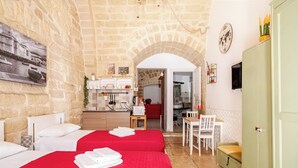 A hotel room with two beds, a kitchenette, a dining area, and an arched doorway leading to another room. - "LULLABY ROOM" APARTMENT BARI. (Bari)