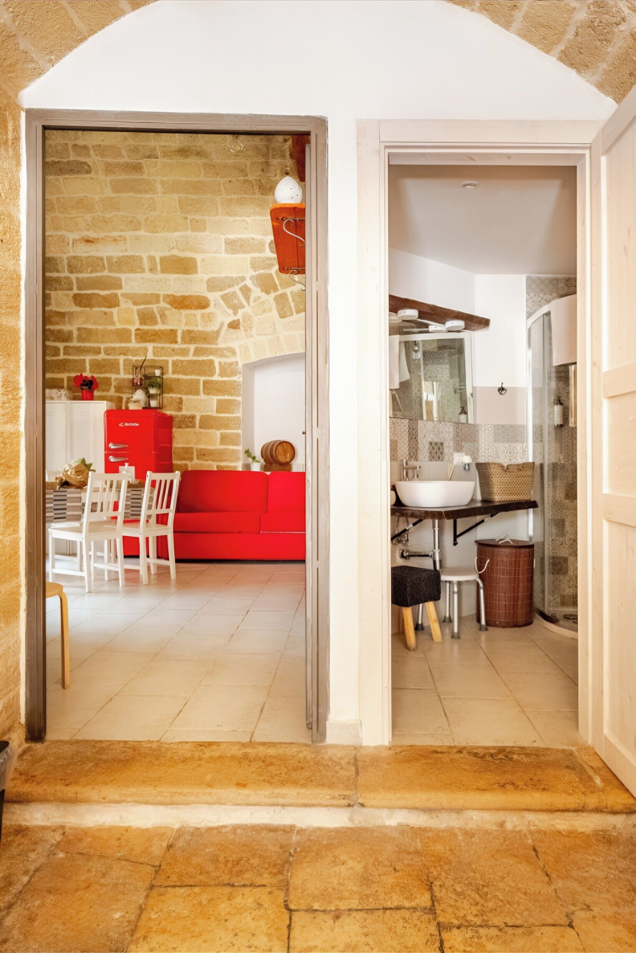 A doorway leading to a living area with a red sofa and a dining table with chairs.
