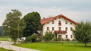 A large, white building with a red roof, surrounded by lush green lawns and trees. - Pension Baumgartner (Rott a.Inn)