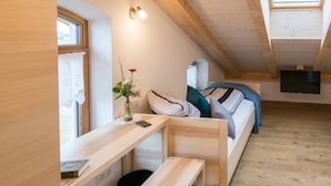 A cozy attic bedroom with a bed, a desk, and a window. - Pension Baumgartner (Rott a.Inn)