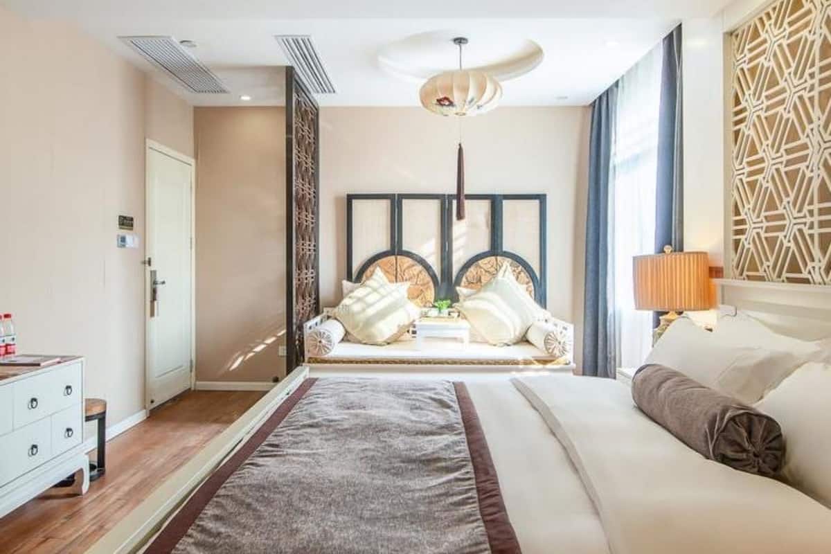 A modern hotel room with a large bed, a sofa, a desk, and a decorative wall panel.