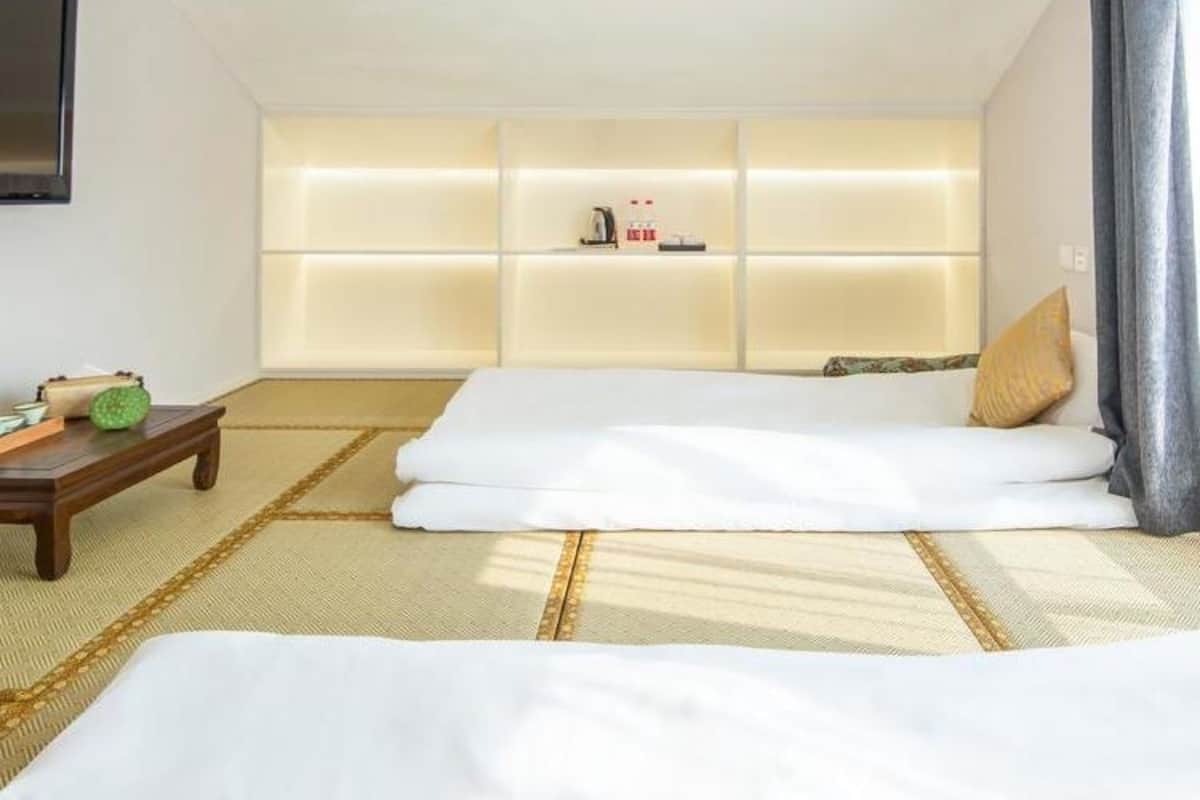 A room with a bed, a small table, and a shelf with items.