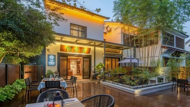 A restaurant with outdoor seating, a covered patio, and a signboard. - Floral Hotel Aranya Resort Hangzhou (Hangzhou)