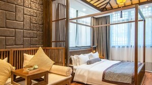 A traditional-style room with a wooden four-poster bed, a sofa with cushions, and a wooden table. - Floral Hotel Aranya Resort Hangzhou (Hangzhou)