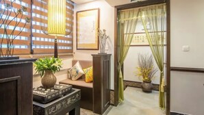 A traditional Japanese room with tatami flooring, a low table with a vase, cushions, and a hanging lamp. - Floral Hotel Aranya Resort Hangzhou (Hangzhou)