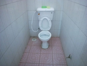 A small bathroom with a toilet, a bidet, and a tiled floor.
