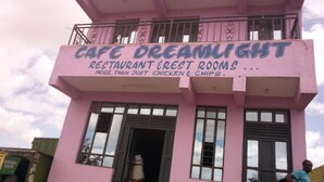 A pink building with a sign that reads "Cafe Dreamlight Restaurant & Rest Rooms." - Dream Light Hotel (Matuu)