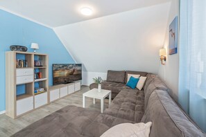 Een moderne woonkamer met een flatscreen televisie, een bank, een salontafel en een boekenkast.