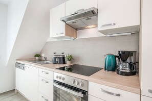 Een moderne keuken met een ingebouwde oven, een kookplaat, een broodrooster en een waterkoker.